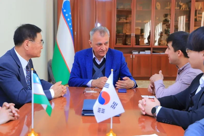 Participants in conversation around a conference table with South Korean and Uzbek desk flags